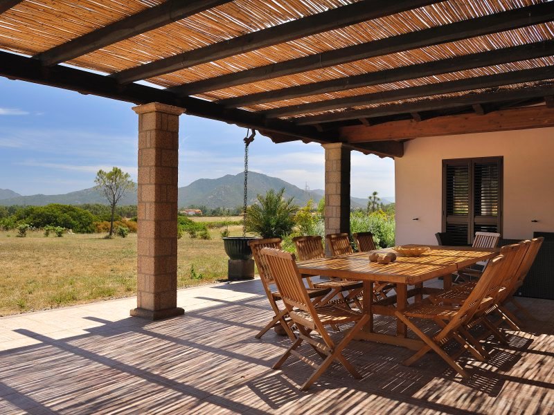 Schattige Terrasse mit Esstisch und Blick auf den Garten Schattige Terrasse mit Esstisch und Blick auf den Garten