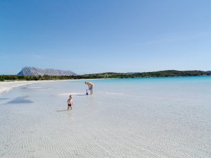 Mutter mit kleinem Kind im glasklaren, seicht abfallenden Wasser von Cala Brandinchi Mutter mit kleinem Kind im glasklaren, seicht abfallenden Wasser von Cala Brandinchi